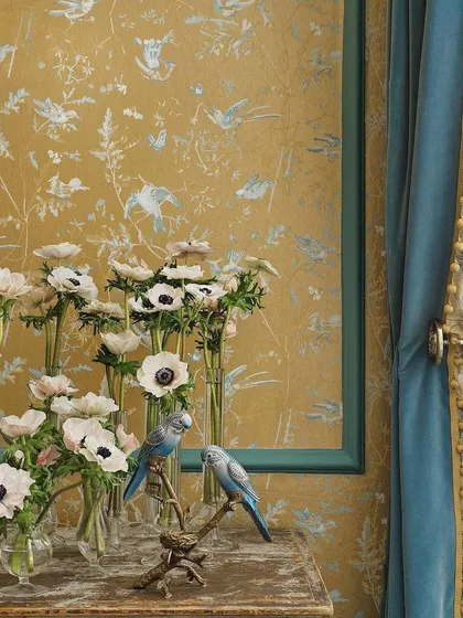 A closer view of the 'Hummingbirds' wallpaper reveals the delicate artistry of the design. Paired with fresh anemones, the scene highlights how this enchanting colorway can awaken any space with its tale of vibrant elegance.