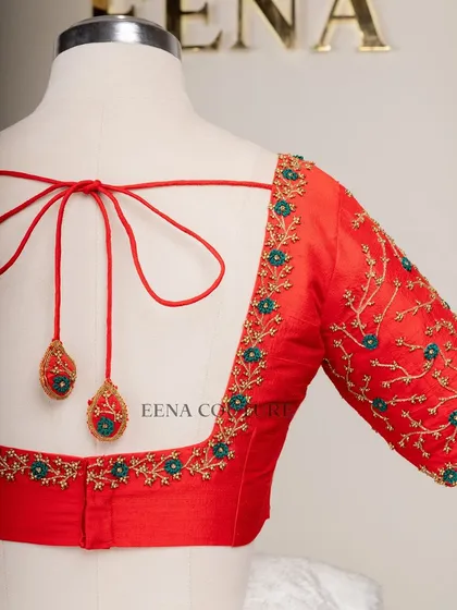 A simple yet striking design. This bright red raw silk blouse features a delicate creeper embroidery pattern in gold and teal thread, with a classic square back and matching handmade tassels.