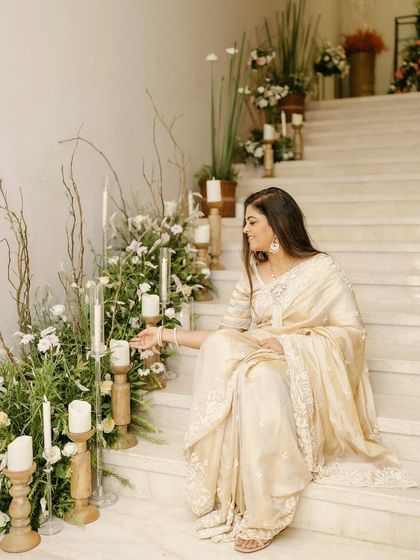 A candid moment from a beautifully styled 50th and 80th birthday celebration. The staircase was decorated with an organic arrangement of white flowers, fresh greenery, and candles in wooden holders, creating a soft, romantic ambiance.