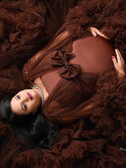 A unique overhead perspective. This artistic shot captures the mom-to-be lying in a bed of rich brown tulle, creating a beautiful texture and pattern.