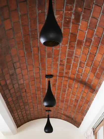 I believe ceilings are a fifth wall waiting for a story. This exposed brick vault ceiling, accented with minimalist pendant lights, creates a warm, dramatic corridor and showcases a love for textural details.