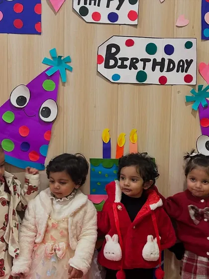 A group of friends gathers for a photo by the birthday decorations.