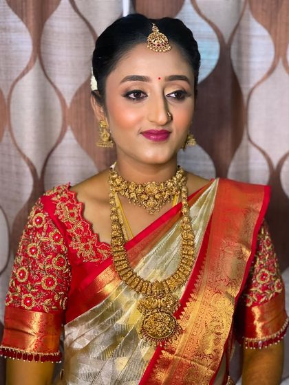 Bride Vidya's Muhurtham look is a testament to timeless beauty. The combination of a white and red Kanchipuram saree with gold jewellery is a classic I love styling.