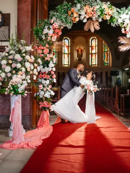 A grand exit from the church, with the groom dipping his bride under a beautiful floral arch.
