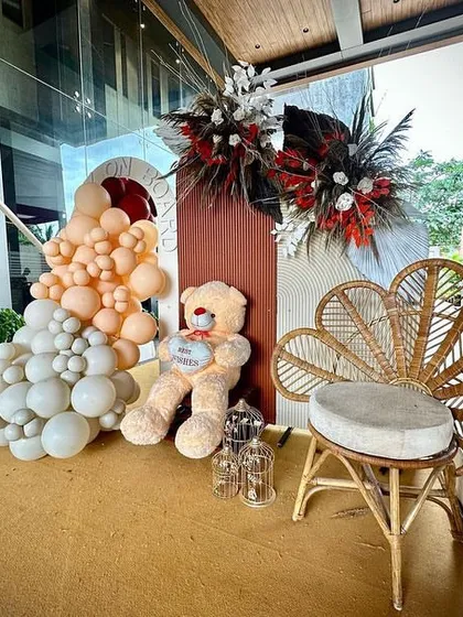 A cozy photo spot featuring a peacock wicker chair and a friendly teddy bear. I use props like these to add personality and create dedicated areas for guests to take memorable pictures.