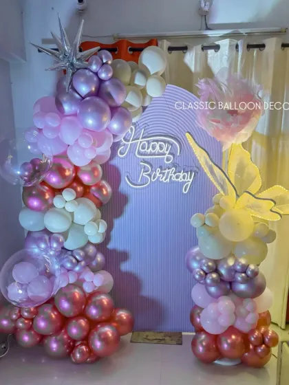 A detailed view of the 40th birthday decor, focusing on the beautiful gradient of pink and purple chrome balloons and the delicate light-up butterfly wing prop.