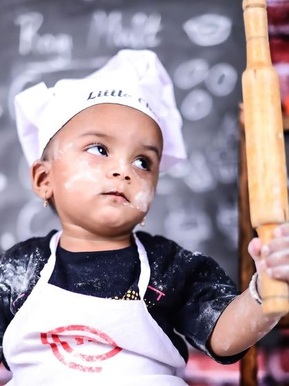 A focused little chef holding a rolling pin, with flour on his face. A perfect candid moment.