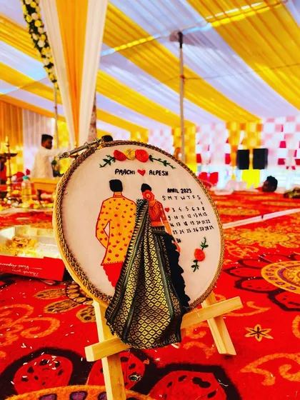 This is a personalized wedding hoop I designed for a lovely couple, Prachi and Alpesh. I love adding special details, like the miniature 3D saree that matches the bride's outfit and a calendar marking their special day. It's a unique piece of hand-embroidered art that they can cherish forever.