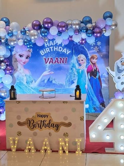 A lovely Frozen themed 4th birthday party with a full stage setup, including character cutouts, a custom backdrop, and a light-up marquee number.