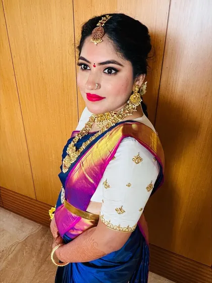 A close up of the side profile. This angle highlights the intricate gold jewellery, the elegant hairstyle, and the perfectly blended makeup.