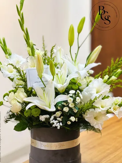 A close-up of a beautiful white floral arrangement in a grey velvet box. The composition of lilies, gladioli, and baby's breath showcases the artistry and freshness of my floral designs.