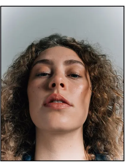 An intense, low-angle close-up portrait for Flanelle Magazine, focusing on the model's direct and confident gaze.