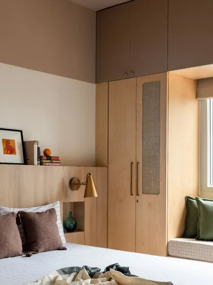 The parent's bedroom features a custom birch plywood headboard with an integrated niche and a window seat for reading. The color-blocked ceiling adds a subtle design element.