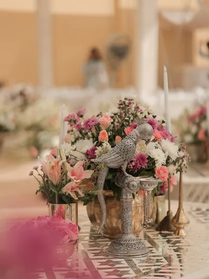 A silver parrot prop perched among pastel florals. It's these small, whimsical details that add character and a touch of the unexpected to a tablescape.