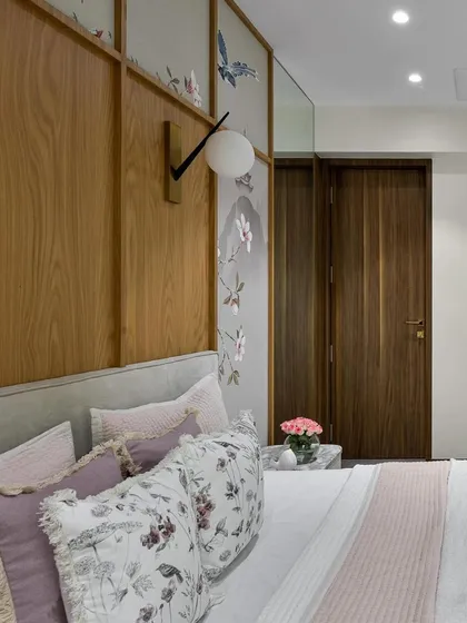 A detailed view of the bedding, showcasing a mix of floral print and solid lavender cushions with delicate fringe details. This combination adds a soft, romantic touch that perfectly complements the Chinoiserie wallpaper in this elegant bedroom.