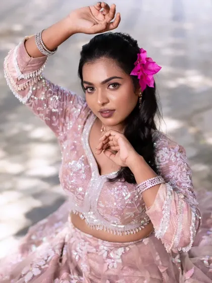 A model showcasing a glamorous look with a pink lehenga and a flower in her hair, perfect inspiration for a reception or sangeet.