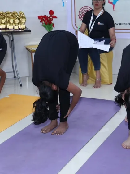 A group of young girls performing Uttanasana (Standing Forward Bend) in unison during the competition. This image captures their focus and the disciplined nature of competitive yogasana.