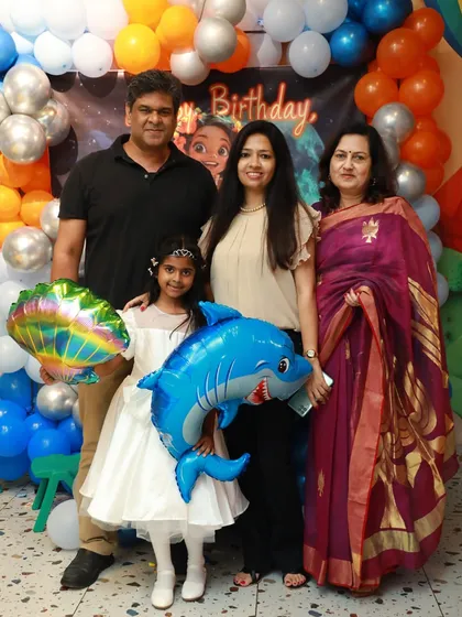 The birthday girl and her family posing with a shark balloon at her under-the-sea party.