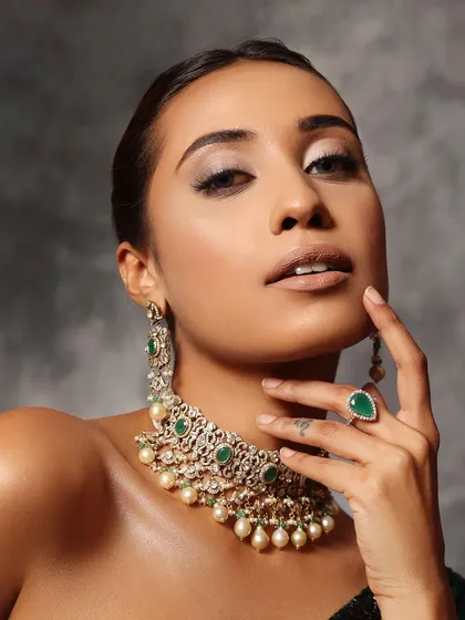 An understated and unforgettable look. The hair is pulled back into a simple, elegant updo, which provides the perfect canvas for dramatic makeup and jewelry.
