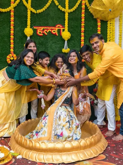 The bride surrounded by her loved ones as they apply Haldi. A moment filled with tradition, love, and laughter.