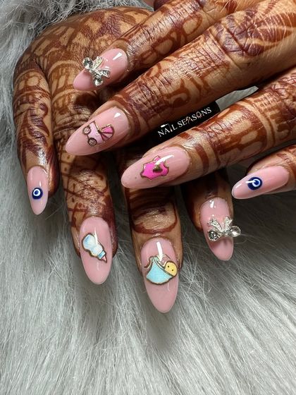 A closer look at the cute details on these baby shower nails, including a baby carriage, a milk bottle, and a little romper.