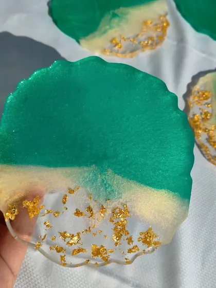 Holding up one of the green and gold resin coasters to show the depth of color and the way the light catches the gold flakes.