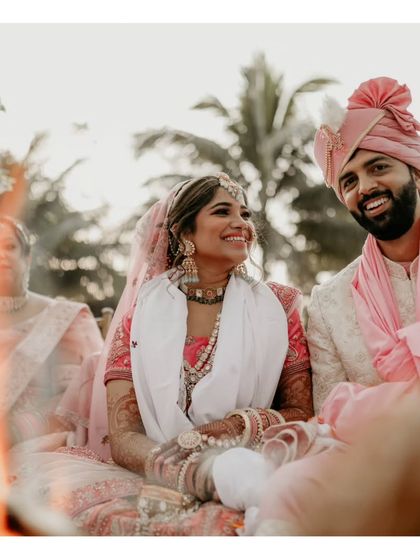The couple seated by the sacred fire, sharing a smile. A warm, intimate shot from the wedding ceremony.