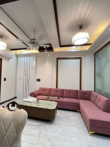 A pop of color can bring a room to life. This dusty rose sectional sofa adds personality and warmth to this living space, complemented by the elegant ceiling design and marble-look flooring.