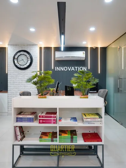 A closer look at the central design elements. The white brick texture wall adds a touch of industrial chic, contrasting with the sleek, dark feature wall. The low-profile bookshelf serves as both storage and a subtle space divider, topped with plants to bring life into the office.