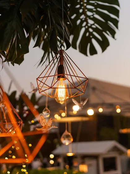 A close-up of the geometric hanging lanterns with Edison bulbs, a modern detail for an outdoor event.
