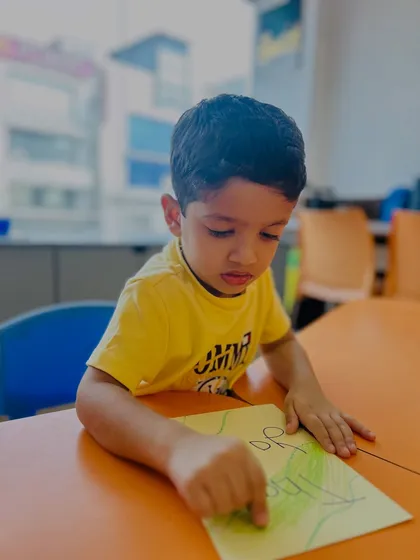 A young boy is deeply focused on coloring his artwork. These quiet, creative moments are just as important as the energetic games for developing concentration.