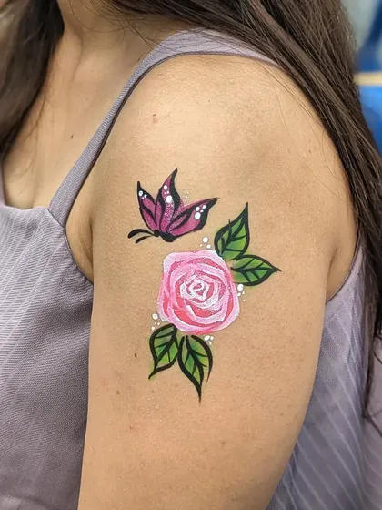 A beautiful combination of a pink rose and a purple butterfly painted on the upper arm.