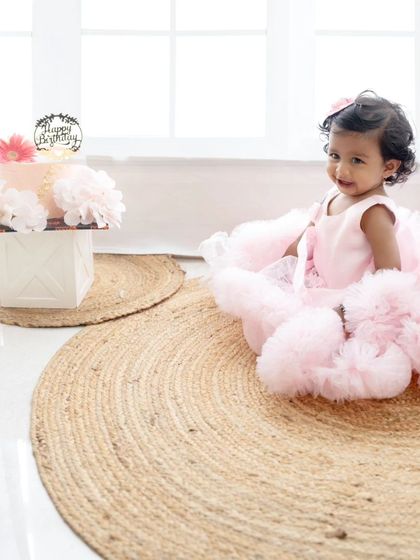 A simple and elegant setup with the birthday girl and her cake on natural jute rugs, creating a soft and beautiful portrait.
