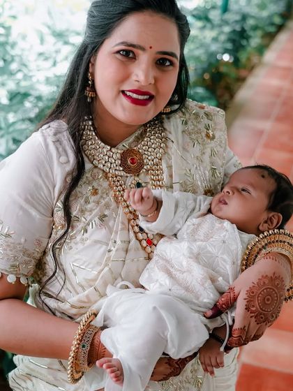 The proud new mother holding one of her twin boys during the naming ceremony. Her joy and the baby's peaceful sleep are beautifully captured.