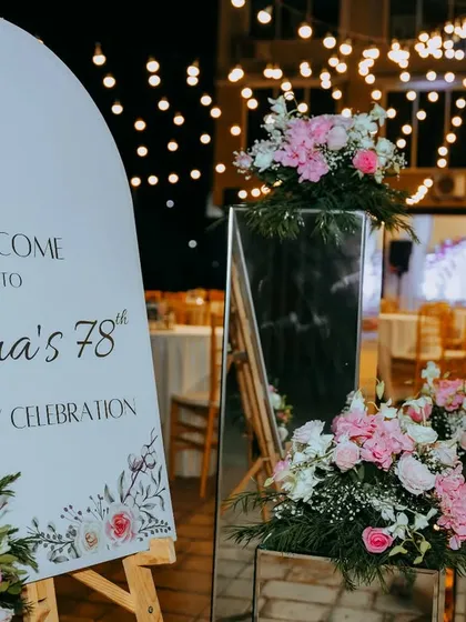 Welcome to the party! A custom arched sign, adorned with delicate floral illustrations, greeted guests at this special 78th birthday celebration, perfectly matching the event's pink and white theme.