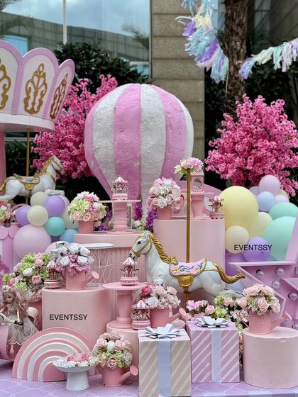 Details of the pastel carnival theme, including carousel horses, gift boxes, and a pink scooter prop.