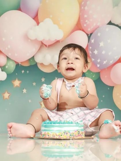 Getting messy during his pre-birthday cake smash! The colorful balloon backdrop and his happy face make this a perfect celebration photo.