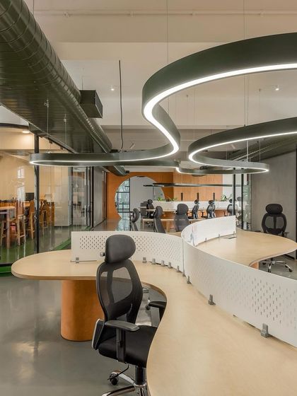A perspective of the open-plan office, showing how the curved workstations and overhead lighting create a sense of movement. The design prioritizes clear sightlines and an unrestrictive layout.