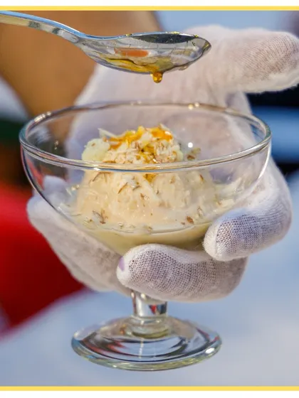 Scooping up smiles with our live ice cream counter. Here, a scoop of ice cream is being drizzled with a sweet syrup, ready to be customized for a guest.