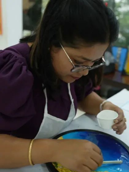 A participant adds details to her resin beach art. The workshop provides all the materials and guidance you need to create a stunning piece.