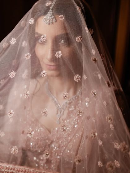 A close-up portrait of the bride looking through her intricately embroidered veil. A shot that is both beautiful and intimate.