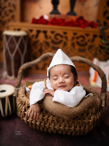 A newborn smiles peacefully while dressed as a little Varkari. Even in sleep, their sweet spirit shines through in these unique, traditional baby photoshoots.