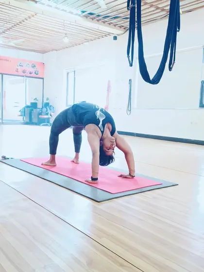 A student demonstrates a perfect Chakrasana (Wheel Pose) in our studio, showcasing her strength and flexibility.