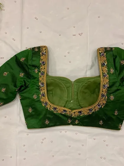 A beautiful bottle green blouse with a sweetheart neckline and delicate buttis embroidered all over.