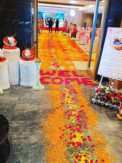 A beautiful flower petal carpet or 'rangoli' at the entrance of a naming ceremony. The welcome sign and traditional 'dahi handi' props add to the festive Krishna theme.