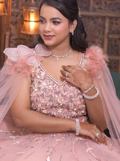 A close-up of a client in a beautiful pink gown with 3D floral and feather details. This is a perfect look for an engagement or pre-wedding photoshoot.