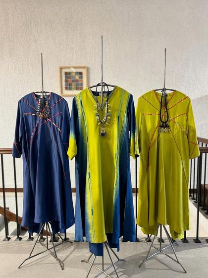 Where art meets attire. A display of three artistic tunic dresses with abstract lines and color-blocking in shades of blue and lime green.