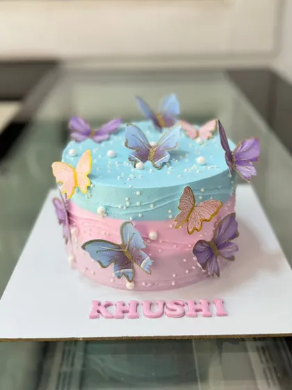 A whimsical butterfly cake with a pink and blue watercolor effect. The edible butterflies seem to flutter around the cake.