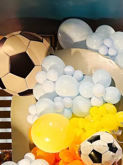 A close-up of a sports-themed party, showing a large football foil balloon as part of the decor.