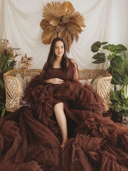 The boho setup provides a beautiful backdrop for solo portraits as well. Here, the expecting mother relaxes on the wicker sofa in a stunning brown ruffled gown.